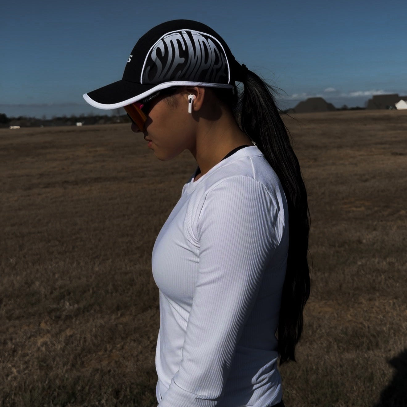 Woman wearing Distance hat and white long-sleeve shirt in an open field