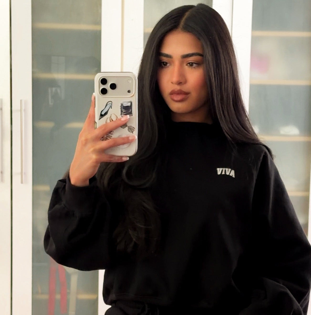 Person wearing a black tracksuit with visible branding, taking a mirror selfie.
