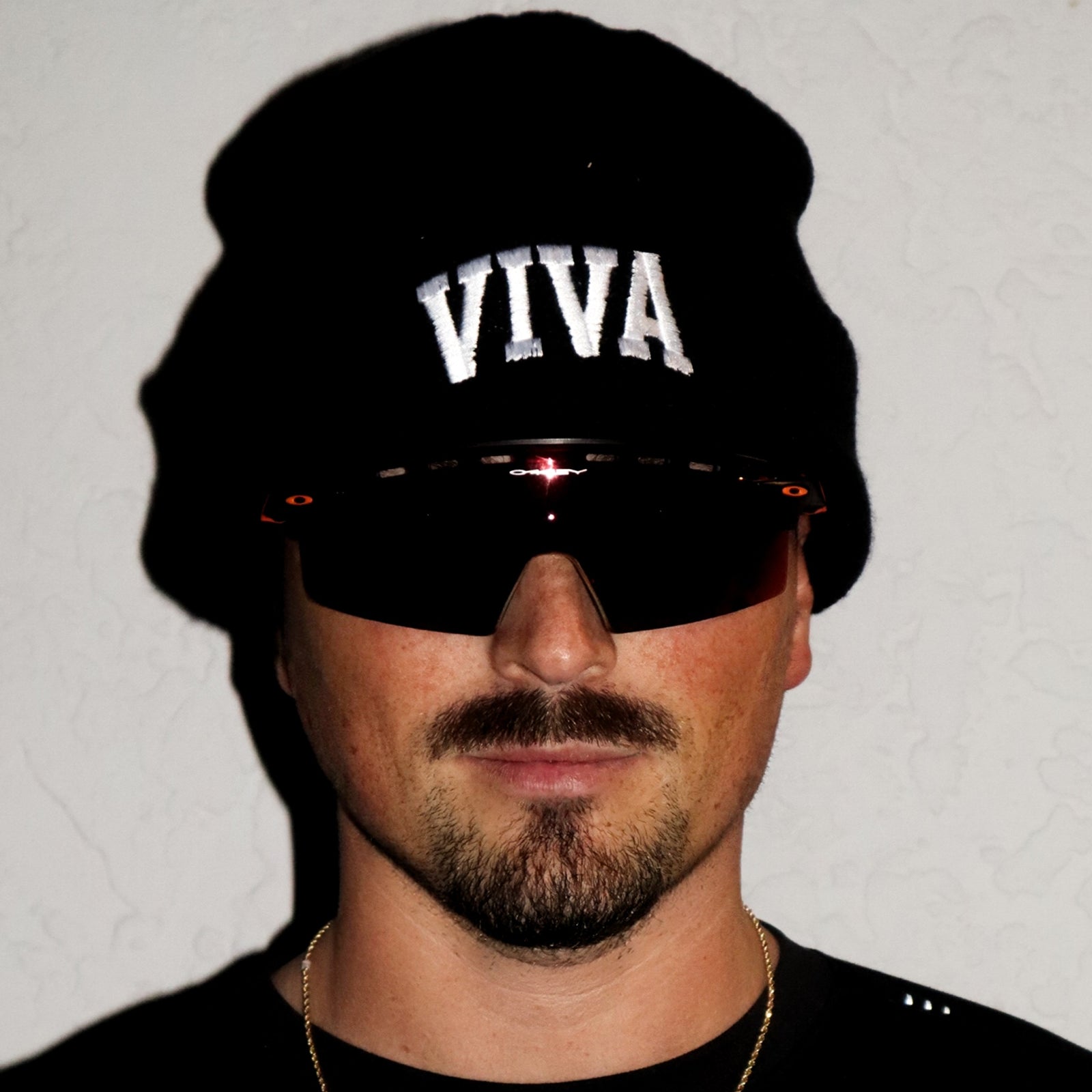 Person wearing a black beanie with 'VIVA' text and sunglasses on a plain background