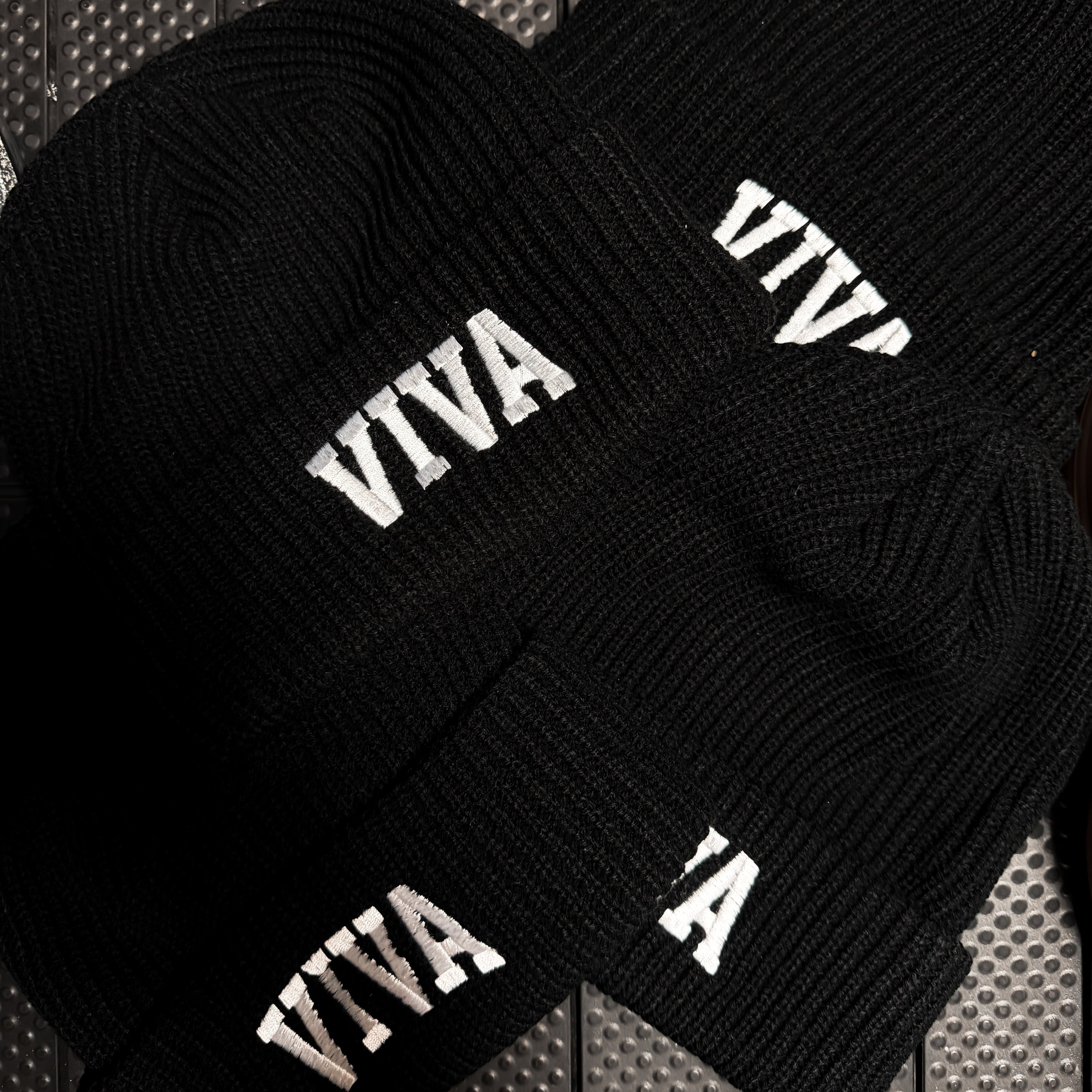 Black beanie with 'VIVA' text on a textured surface